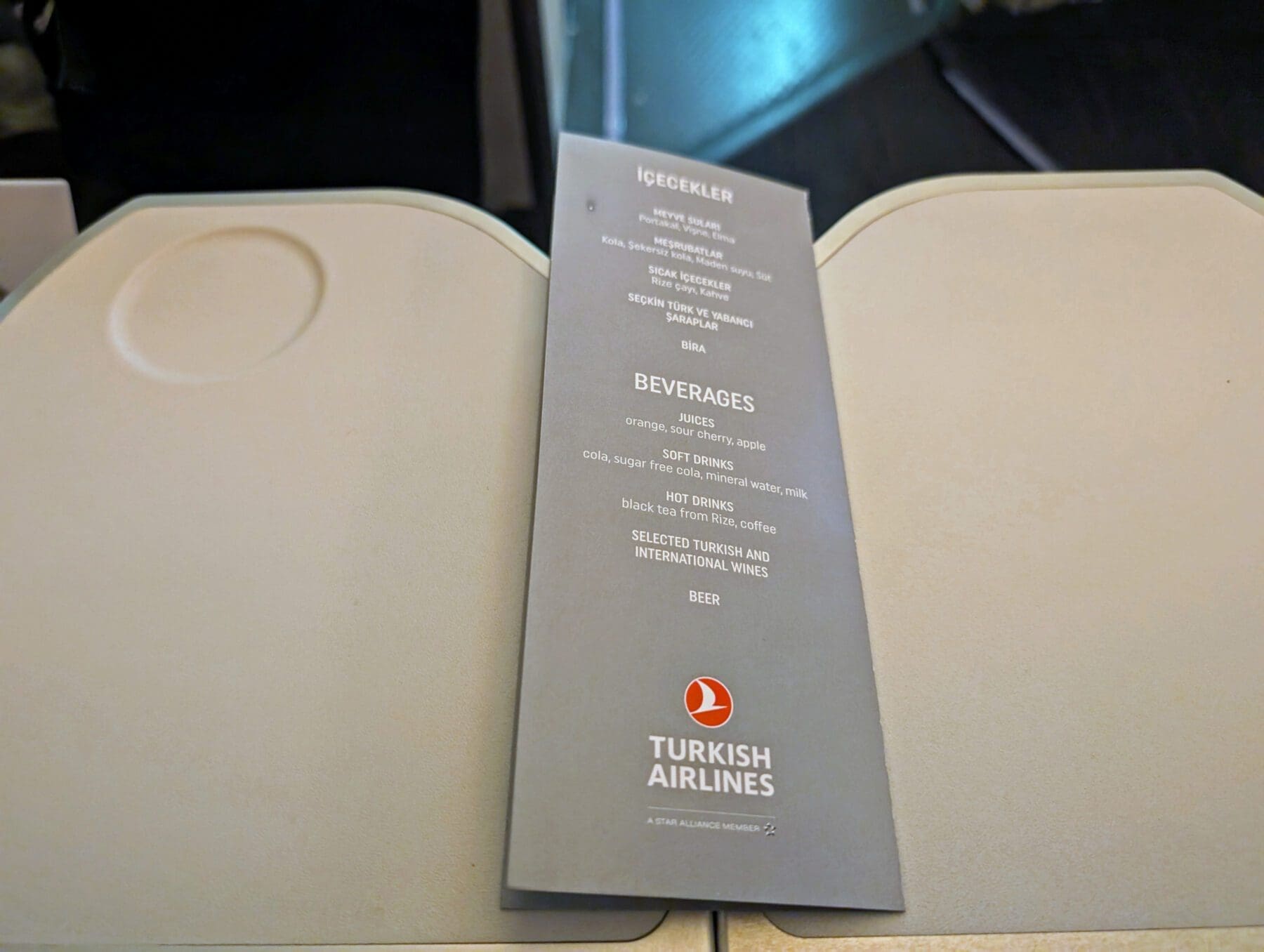 Turkish Airlines Food Review Economy Class 11 The Turkish Airlines menu, elegantly placed on a tray table, showcases their delicious meals alongside a selection of beverages including tea, coffee, juices, and wines.