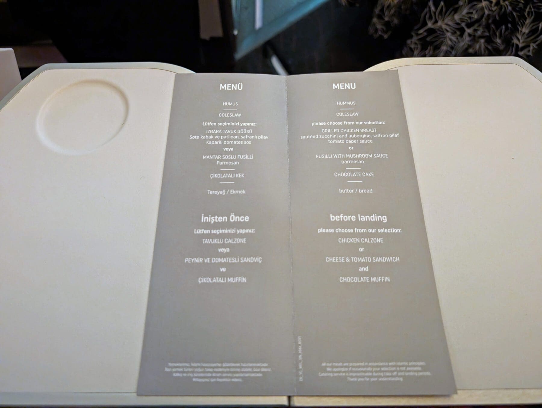 Turkish Airlines Food Review Economy Class 10 On a Turkish Airlines meal tray table, savor the exquisite options for breakfast and before landing, featuring chicken calzone, cheese sandwich, and a delectable chocolate muffin.