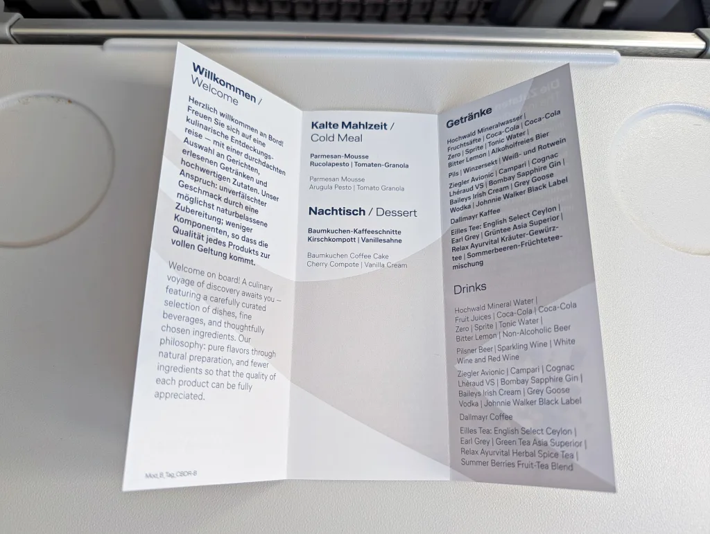 Lufthansa: Paris to Toulouse 3 An airline meal menu displayed on a tray table, printed in German and English, listing options for cold meal, dessert, and drinks.